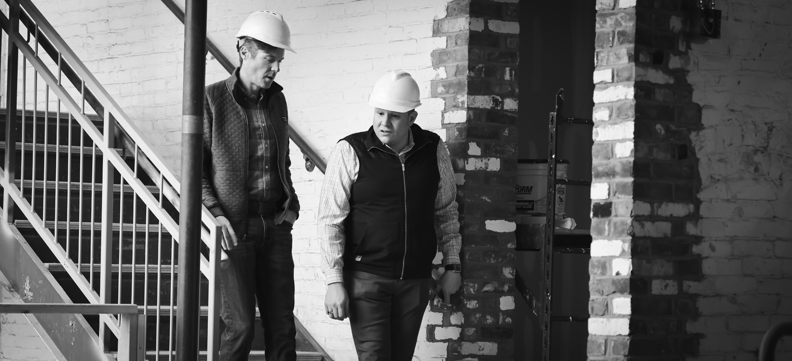 black and white photo of partners Ryan Gorman and Brian Iammartino btcRE founders walking down a stairwell during a renovation